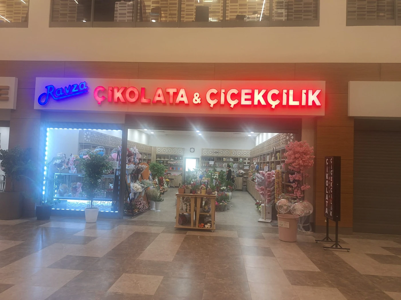 Ravza Çikolata ve Çiçekçilik mağazası; mavi Ravza yazısı ve kırmızı tabelası